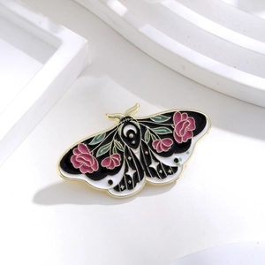 Detail of moth enamel pin featuring pink roses, crescent moon and gold metallic edges