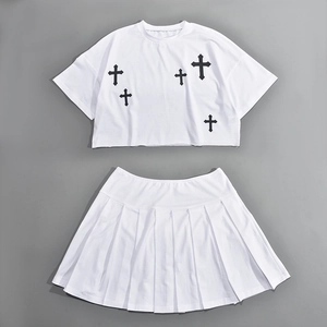 Dettaglio del set bianco a due pezzi con crop top stampa croce e gonna a pieghe corta