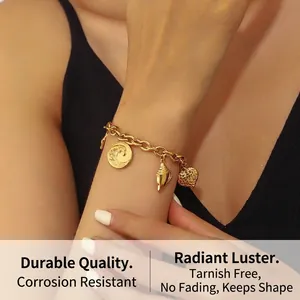 Detail of gold-plated thick chain bracelet with engraved wave disc and seashell charms