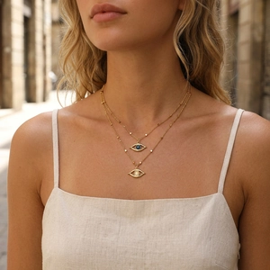 Close-up of double-layered evil eye necklace with blue and white stones on female model