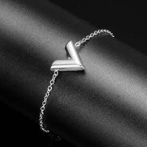 Macro shot of a silver V-shaped pendant on a chain over a black leather texture
