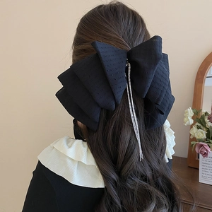 Elegant large black lace bow hair clip with sparkling rhinestone tassels on wavy hair