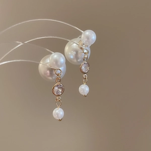 Detail of silver needle pearl earrings with gold chain and cubic zirconia accents