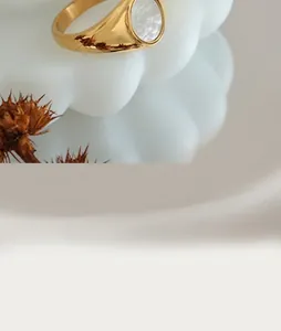 Close-up of a gold signet ring with a white shell inlay on a white ceramic tray