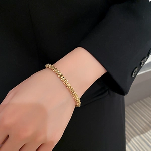 Close-up of a gold geometric textured open cuff bracelet worn on a model's wrist