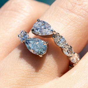 Elegant bypass ring with pear-shaped white and light blue stones and pavé accents