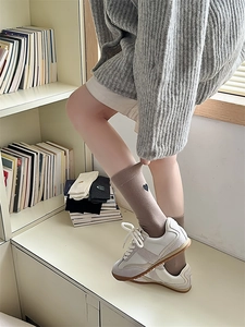 Detail of khaki cotton mid-tube sock featuring a small black embroidered heart on the cuff