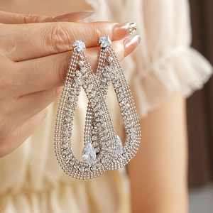 Detailed close-up of a silver mesh drop earring with teardrop and square zircons