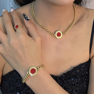 Golden Cuban chain jewelry set with red circular charms worn by a female model