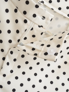 Detailed close-up of polka dot fabric shorts with waist zipper and transparent button closure