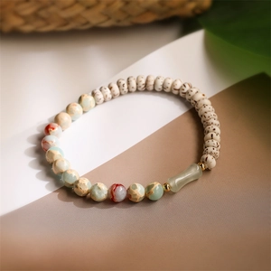 Detail of natural agate and wood beads bracelet with green jade tube on a zen background