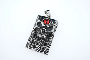 Macro detail of silver skull pendant with red gemstone eye in gothic punk style