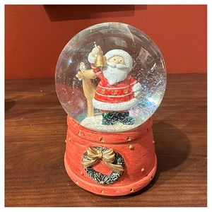 Detail of Santa Claus and reindeer inside a snow globe with a red festive resin base