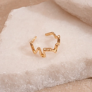 Macro detail of gold wavy irregular textured ring on natural stone background