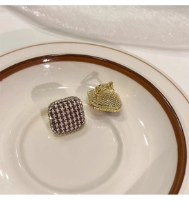 Detail of square houndstooth fabric earrings with gold border and sparkling crystals