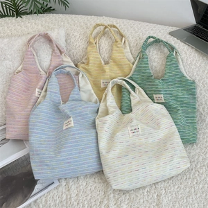 Detailed pile of colorful woven tote bags in pink, yellow, blue, green and white colors