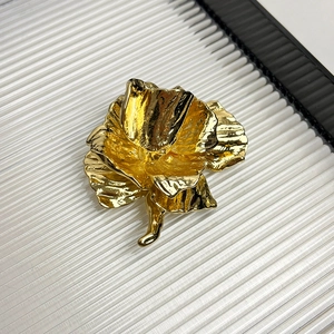 Close-up of a vintage golden rose brooch with polished metallic texture and detailed petals