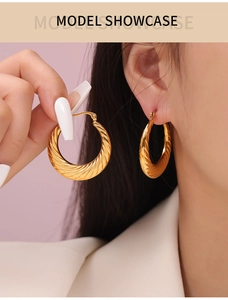 Detail of gold titanium steel hoop earrings with elegant spiral twisted texture design