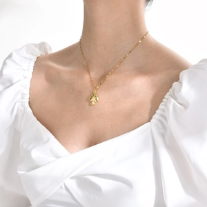 Golden mushroom pendant necklace on model's collarbone with a delicate chain