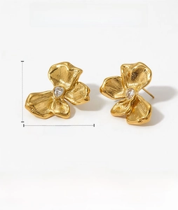 Detail view of golden flower earrings with water drop zircon and brushed metal texture