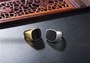 Macro detail of gold and silver square signet rings with black enamel inlay surfaces