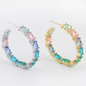 Detailed close-up of large C-shaped hoop earrings featuring multi-color oval cubic zirconia