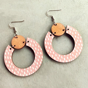 Modern Bohemian geometric wood drop earrings with pink and white polka dots on grey surface