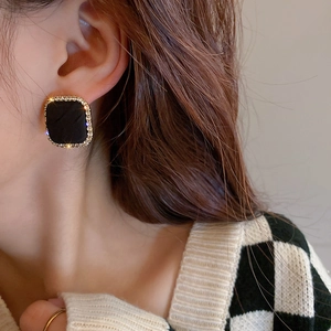 Close-up of a square houndstooth heart earring with gold rhinestones on a female model