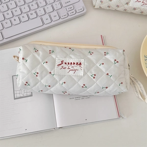 Vue macro d'une trousse à maquillage blanche matelassée à imprimé cerises sur un bureau