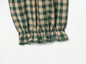 Detail of green and yellow plaid shirt sleeve with elastic smocked cuff and linen texture