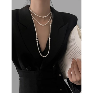 Close-up of layered pearl necklace with varying bead sizes on a black blazer