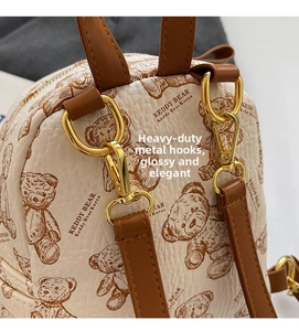 Détail du sac à dos en cuir beige avec motif d'ours et crochets en métal doré