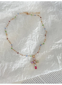Détail du collier croix en zircon coloré avec une chaîne dorée et fermoir mousqueton