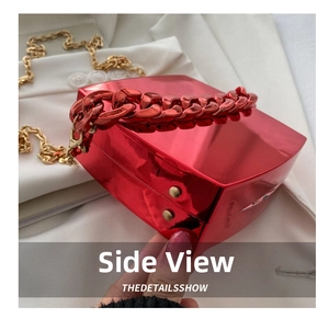 Close-up of red glossy hardshell bag featuring chunky chain and gold metal clasps