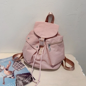 Detailed view of pink nylon backpack featuring flap closure, buckle, and drawstring design