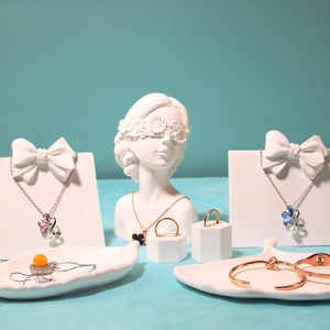 Artistic jewelry display set featuring clover necklaces and rings on plaster busts
