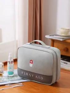 Detailed view of grey first aid kit bag with cross logo and handle on wooden table