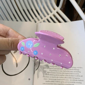 Détail de la pince à cheveux fleur rose en acétate avec strass et motif rayé