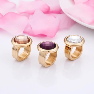 Three gold titanium rings with amber, purple, and white faceted glass stones