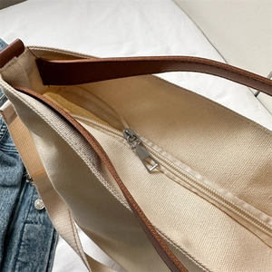Minimalist canvas tote bag with brown faux leather straps and silver zipper top view