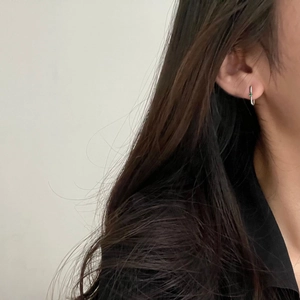 Close-up of minimalist 925 silver hoop earrings with green zircon on woman's ear