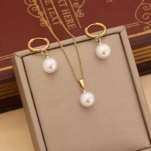 Classic gold jewelry set with white imitation pearl necklace and earrings on a gift box