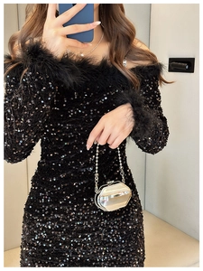 Detailed view of black sequin dress with feather trim and a mini gold chain bag