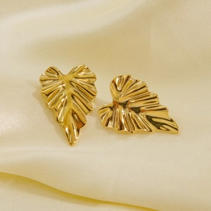 Polished gold leaf-shaped titanium steel earrings on a soft beige satin fabric background
