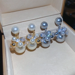 Détail de boucles d'oreilles en perles blanches et gris-bleu avec placage en or 14 carats