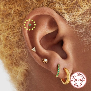 Macro view of 925 sterling silver gold-plated cartilage stud with green zircon inlay