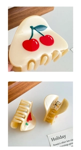 Detailed view of cream acetate hair claw clips with red cherry and rose floral patterns