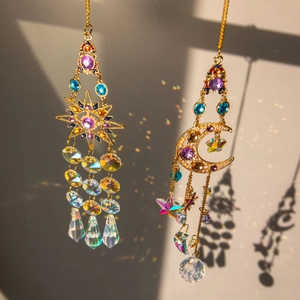 Golden sun and moon crystal suncatchers casting rainbow light on a soft wall