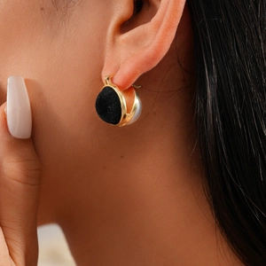 Close-up of vintage black flocked and pearl geometric hoop earrings with gold metal edges