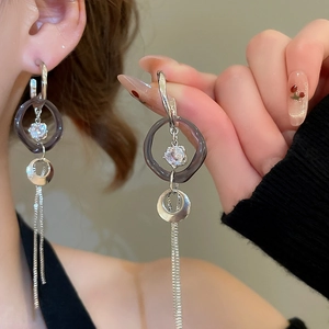 Détail de boucles d'oreilles en C avec anneaux acryliques, zircons et longs glands